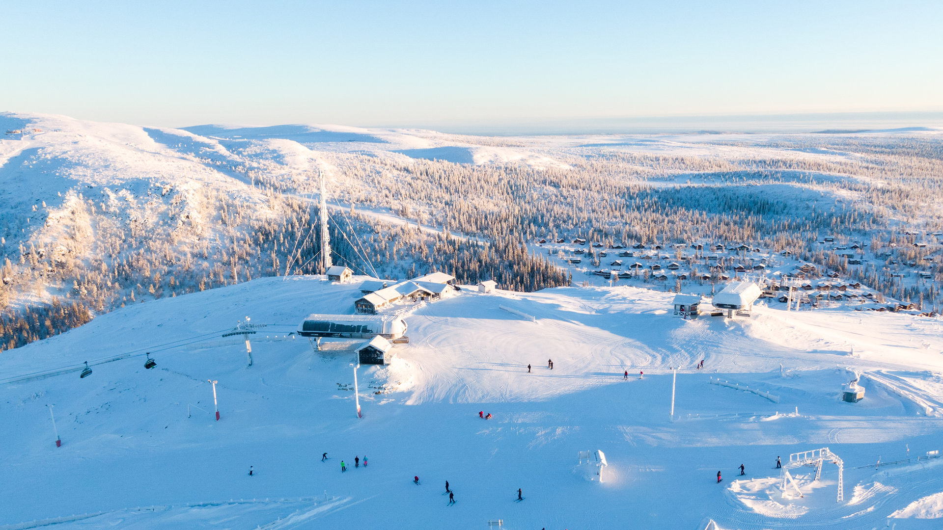 Winter landscape over a ski area, with lifts and powder snow surrounded by snow-covered mountains and forest